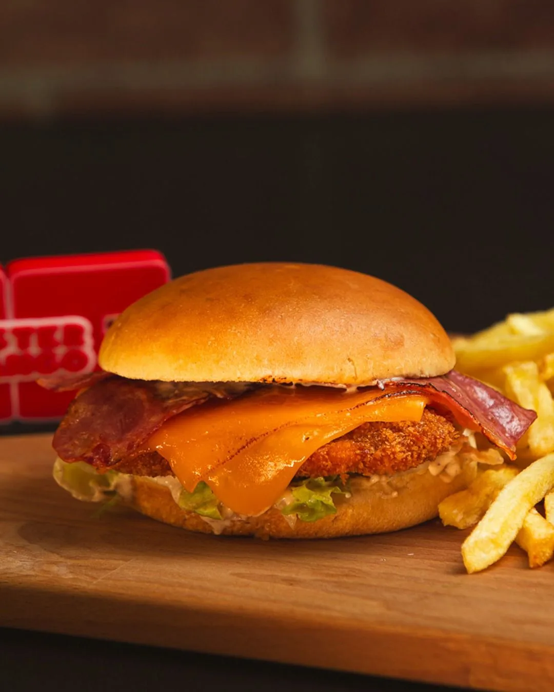 Sanduíche Mister Crispy com bacon e queijo, ao lado de batata frita